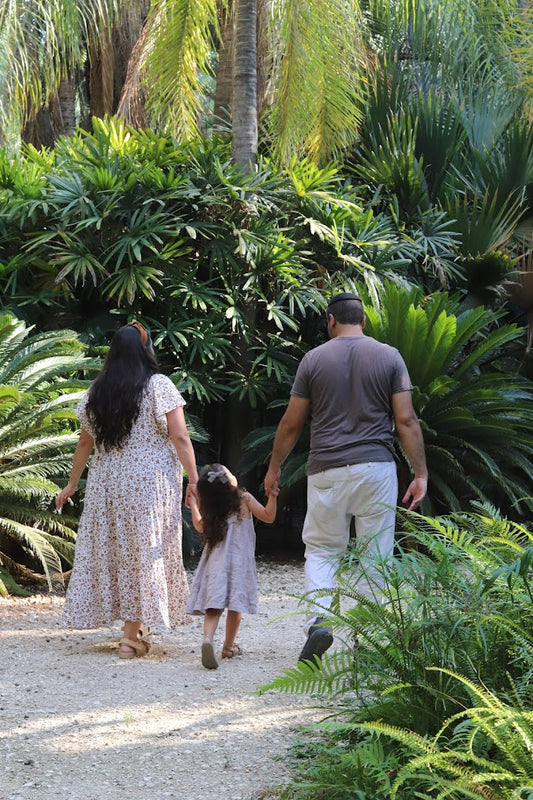 Family walks through jungle-scape, hand in hand